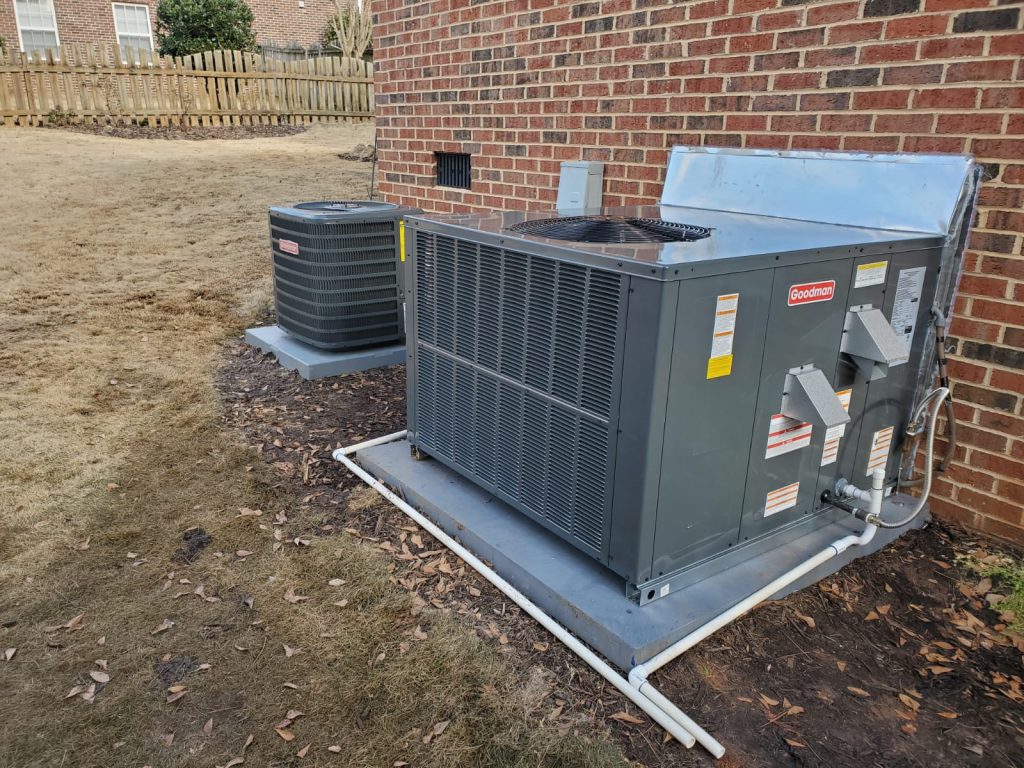 Two outdoor air conditioning condenser units installed beside a brick house with connecting refrigerant and electrical lines.”